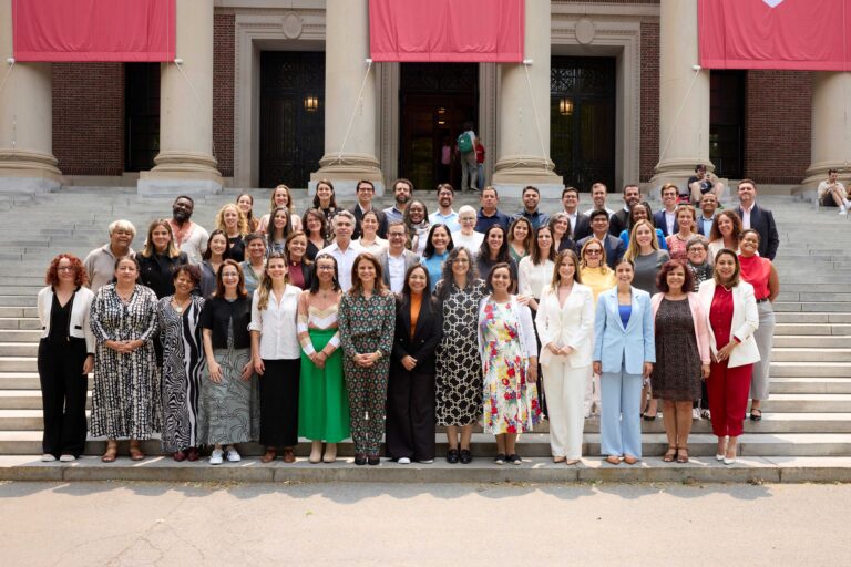 Grupo com cerca de 50 pessoas posicionadas em quatro filas, uma atrás da outra, na escadaria em frente à biblioteca da Universidade Harvard
