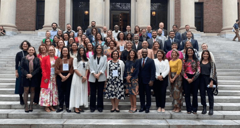 Grupo com cerca de 50 pessoas posicionadas em quatro filas, uma atrás da outra, na escadaria em frente à biblioteca da Universidade Harvard